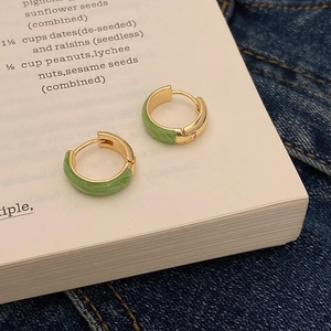 Detailansicht der goldenen Creolen mit grüner Emaille auf einer Buchseite