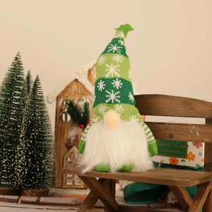 Close-up of a glowing Christmas gnome doll with snowflake knit hat on a wooden stool
