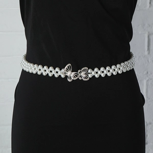 Detail of multi-strand pearl belt with rhinestone butterfly buckle on black fabric