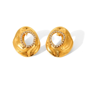 Macro detail of gold earrings featuring irregular lava texture and white rhinestones