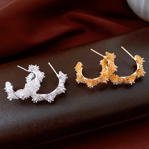 Détail de boucles d'oreilles fleurs en C plaquées or 18 carats et argent avec zircon