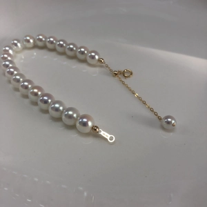 Macro detail of high-luster white pearls and 14k gold-plated clasp on elegant bracelet
