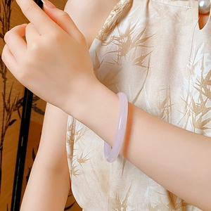 Close-up of a translucent lavender jade bangle on a wrist with New Chinese style elements