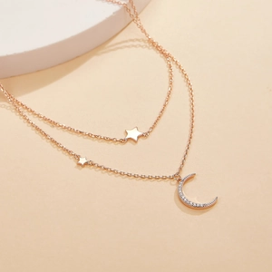 Detail of rose gold double layer necklace with micro-paved moon and star pendants
