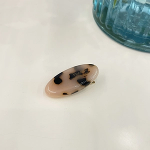 Close-up of tortoise shell pattern acetate hair clip with gold France Handmade lettering