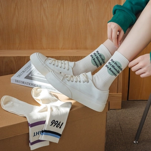 Vue détaillée de chaussettes en coton blanc avec cercles verts et texte brodé Be Grateful