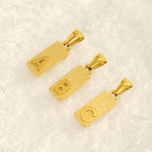 Gold rectangular titanium steel alphabet pendants with A, B, C letters on a textured surface