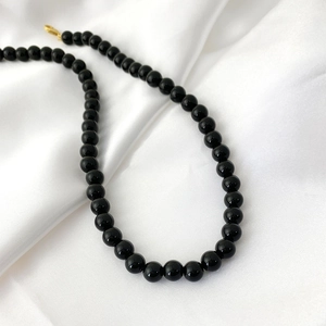 Detail of elegant black onyx beads on silk fabric with a secure gold clasp closure