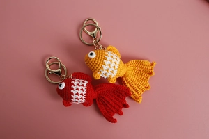 Detail of red and orange crochet goldfish keychains showing handmade yarn textures