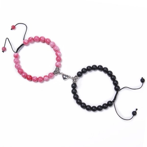 Close-up of pink and black bead bracelets with silver magnetic heart clasp on white background