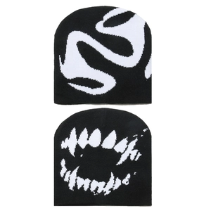 Close-up detail of knitted beanies featuring abstract white graphic patterns on black