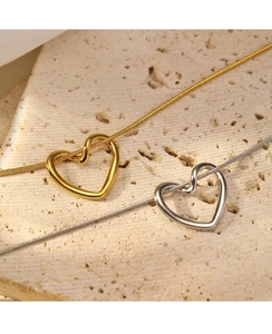 Close-up of minimalist gold and silver twisted heart pendants on sleek snake chains