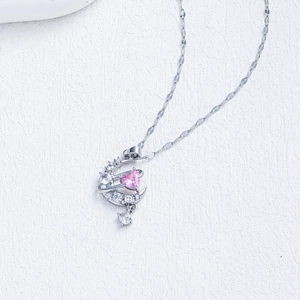 Macro detail of crescent moon pendant with pink heart stone and sparkling diamonds