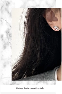 Close-up of minimalist silver knot stud earrings worn by a model in a creative style