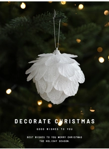 White pine cone Christmas ornament with glitter finish hanging on a festive tree branch