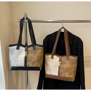 Two-tone tote bags in cream and brown leather shown on a stand and fashion mannequin