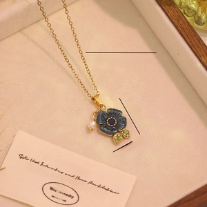 Détail du pendentif rose bleue avec perles sur une chaîne en acier inoxydable doré