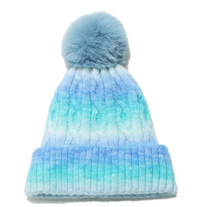 Detail of cable knit pattern and faux fur pompom on blue gradient winter beanie