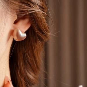 Gros plan d'une boucle d'oreille en cœur doré et résine nacrée sur l'oreille d'un mannequin