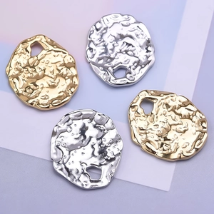 Detailed view of textured oval 304 stainless steel pendants in gold and silver finishes