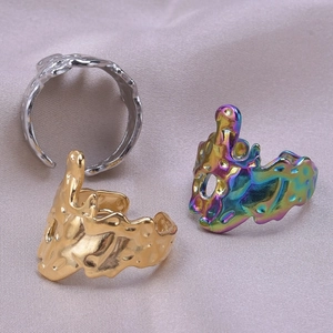Close-up of irregular liquid metal rings in gold, silver and rainbow finish on silk