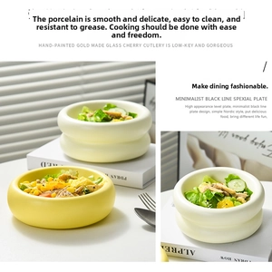 Close-up of minimalist ceramic donut-shaped bowls in creamy white and yellow for salad and soup