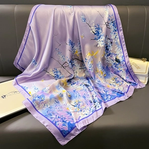 Elegant purple silk scarf with yellow and blue floral patterns on a leather sofa