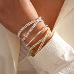 Close-up of stacked gold and silver geometric bracelets with rhinestones on model wrist