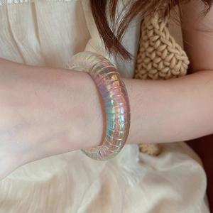 Detail of an iridescent acrylic bangle with ribbed texture and multi-color gradient sheen