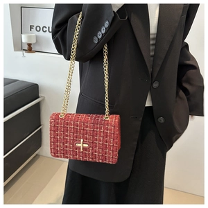 Détail du sac en tweed rouge avec chaîne dorée et fermoir rotatif sur un blazer noir