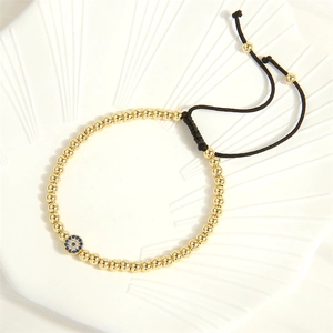 Close-up of golden beaded bracelet featuring a blue gemstone evil eye charm
