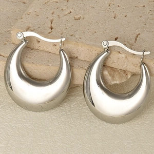 Macro detail of chunky silver hoop earrings with high-polish mirror finish on stone surface