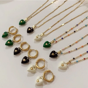 Detail of heart-shaped pendants and earrings set in colorful enamel with gold-plated finish