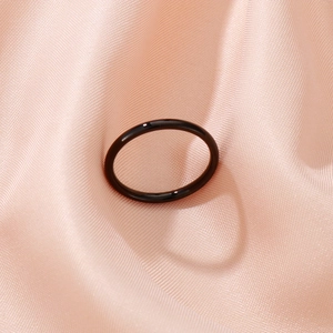 Polished black minimalist band ring shown on elegant pink silk fabric background