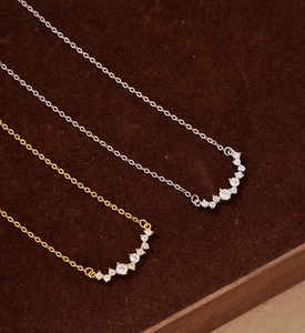 Detailed close-up of gold and silver smile necklaces with zircon pavé on velvet background