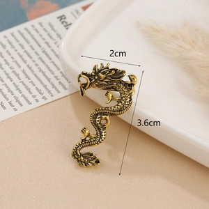 Vintage golden dragon brooch with intricate scales on white ceramic tray, 3.6x2cm size