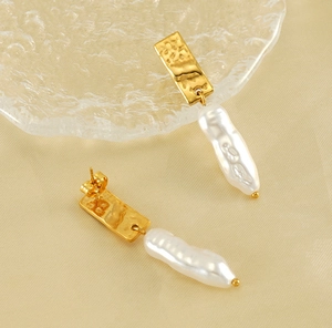Close-up of gold hammered metal and baroque pearl earrings on silk background