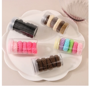 Close-up of five jars containing soft jacquard plush hair ties in assorted colors