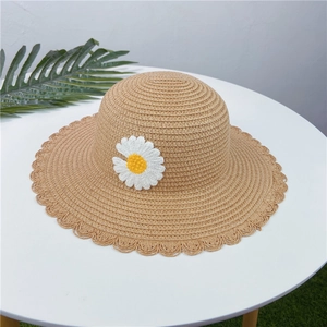 Gros plan d'un chapeau de paille pour enfants avec marguerite crochetée à la main.