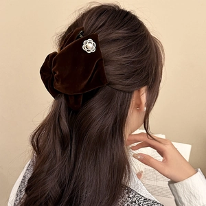 Detail view of a velvet bow hair claw clip with metallic floral decor and white pearl accent