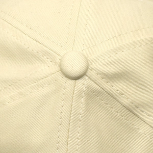 Macro detail of high-density cotton twill seams and top button on a beige baseball cap