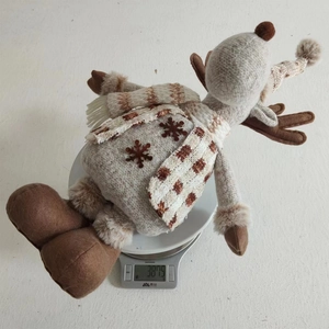 Detailed view of weighted Christmas reindeer plush toy on a digital kitchen scale