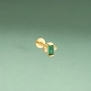 Detailed close-up of golden diamond earring with emerald green rectangular zircon stone