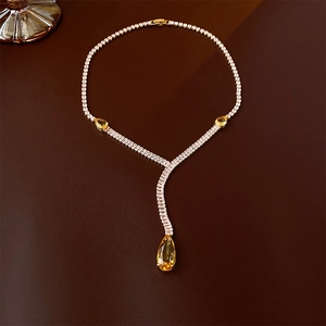 Close-up of golden necklace with yellow pear-shaped gemstones and sparkling clear crystals