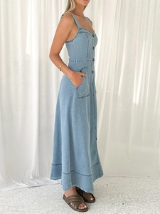 Dettaglio di un abito lungo in denim celeste con tasche cargo laterali e bottoni