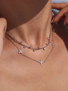 Macro shot of silver snake chain and layered necklace with cross pendants on neck
