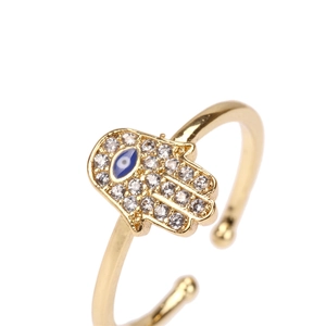 Macro shot of gold-plated Hamsa hand ring featuring blue evil eye and zircon stones