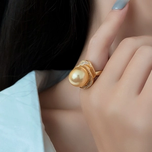 Close-up of a luxury gold ring featuring a large golden pearl and pave-set zircons