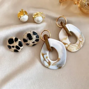 Three-piece French vintage earring set with pearls and resin drops on silk background