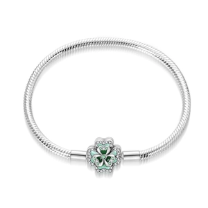 Detail of silver snake chain bracelet with green enamel and zircon clover charm